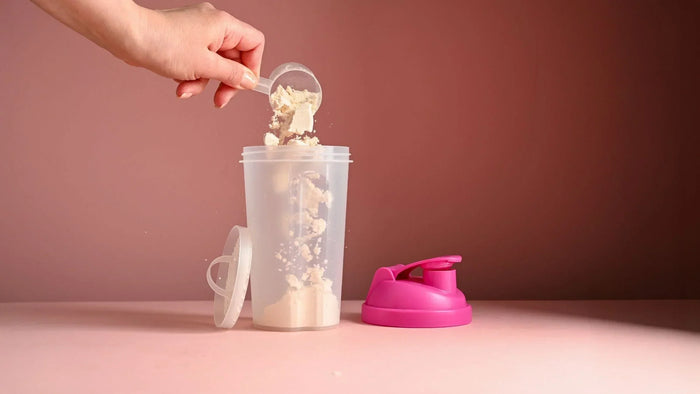 MaxiMeal complete meal shake put in shaker bottle with pink lid on a pink background