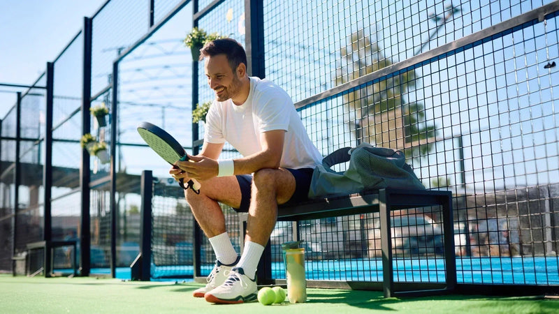 Adult man drinking from a bottle while resting on an outdoor padel court, illustrating recovery and nutrition needs for active adults training over 30 for MaxiMeal Blog