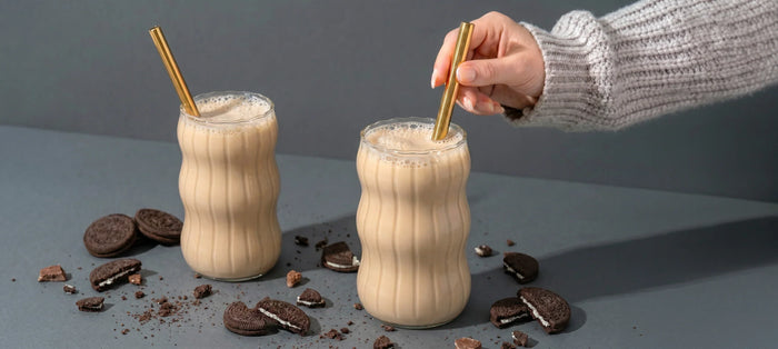 Two MaxiMeal Original Shakes in glasses with cookie crumbs and a straw